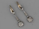 two pairs of diamond earrings on a gray surface