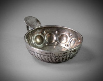 an old silver bowl with a spoon in it on a table