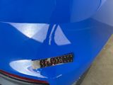 the rear end of a blue car with a sticker on it ' s bumper