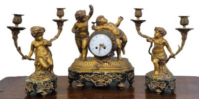 des figurines en laiton posées sur une table en bois, avec une horloge et des bougies