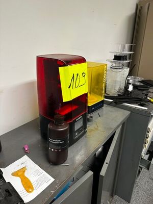 un mixeur rouge posé sur un bureau, à côté d'un panneau jaune