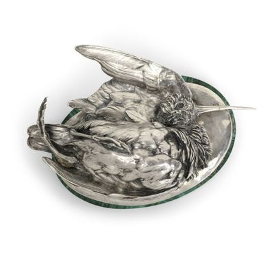 une assiette en argent ornée d'un oiseau sur un fond blanc