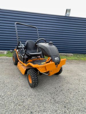 une tondeuse autoportée orange garée devant un mur bleu