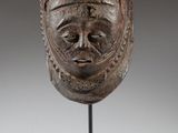 a close up of a wooden mask on a stand on a white background