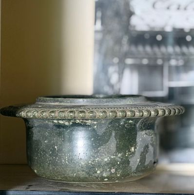 a pot that is sitting on a shelf in front of a clock