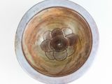 a brown and white bowl with a flower on it