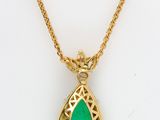 a gold necklace with a green tear shaped pendant on a gold chain