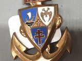 une ancre dorée ornée d'une croix et un blason bleu et blanc