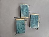 three small blue glass tiles mounted on a wall
