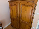 une armoire en bois placée dans un coin de la pièce, avec une chaise à côté