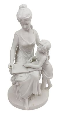 statue représentant une femme lisant un livre à un enfant assis sur un tabouret