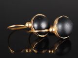une photo d'une paire de boucles d'oreilles en or et pierres noires