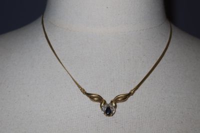 gold plated necklace with a blue crystal stone on a mannequin neck