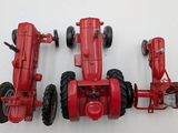 two red toy tractors sitting next to each other on a white surface