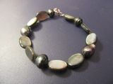 bracelet composé de perles en nacre et d'argent sur un fond noir