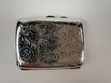 a small silver box with a floral design on it