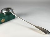 une cuillère en argent et une boîte verte posées sur une table
