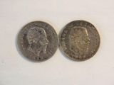 two silver coins sitting side by side on a white surface