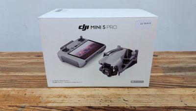 Drone DJI Mini Mini avec son coffret d'accessoires posé sur une table en bois