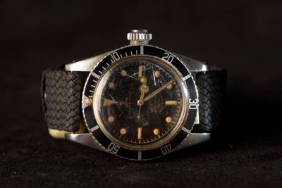an image of a watch on a black surface with a black background
