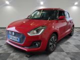 Une Suzuki Swift rouge est garée dans une pièce au sol à carreaux.