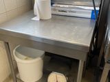 table de travail en acier inoxydable sur laquelle se trouvent deux seaux et deux rouleaux de papier toilette