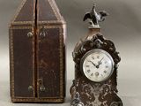 a small clock sitting next to a box with a bird on top of it