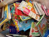 a pile of children ' s books in a bin on the floor