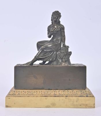 statue en bronze représentant une femme assise sur un rocher, tenant un panier de fleurs