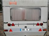 a small white trailer parked in the dirt