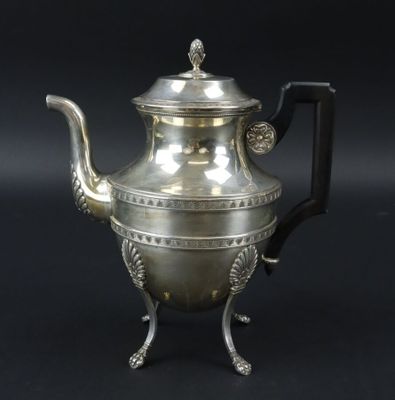 une théière ancienne en argent avec une anse, sur fond noir