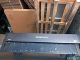 une table sur laquelle est posée une règle, devant une pile de cartons