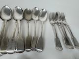 six spoons and six forks laid out on a table