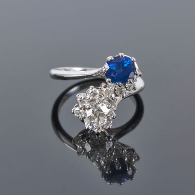 a close up of a sapphire and diamond ring on a reflective surface