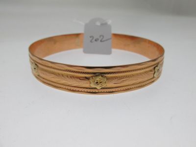 gros plan d'un bracelet en or sur une surface blanche