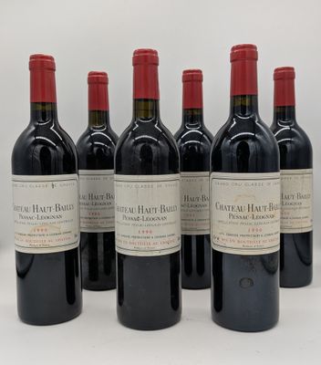 six bouteilles de vin rouge sont alignées sur une surface blanche