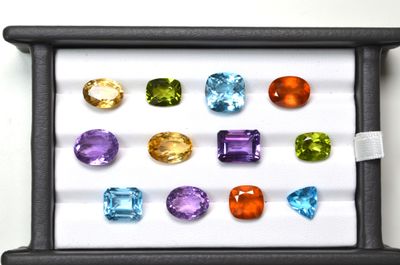 several different colored gems in a black box on a white surface
