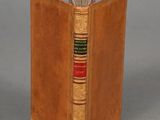 an old book with a leather cover sitting on top of a table