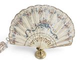 a white fan with floral designs on it and a tassel