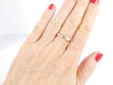 a woman ' s hand with a red manicure and a gold ring