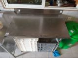 a stainless steel table with a green bag on the floor