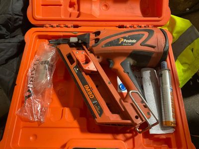 une boîte à outils orange contenant une agrafeuse, un pistolet à clous et d'autres outils