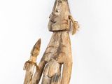 an old wooden statue of a man holding a bird in his hand