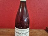 La bouteille de vin est posée sur la table, devant un mur rouge.