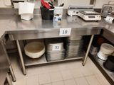 une table en acier inoxydable sur laquelle sont posées de nombreuses assiettes et casseroles