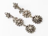 a pair of silver earrings with flowers and leaves on them