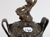 an antique bronze vase with a boy on top of it