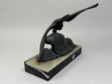 a statue of a woman sitting on a rock with a bird in her hand