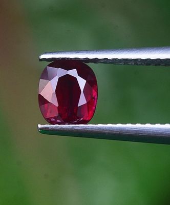 un gros plan d'un diamant rouge tenu par une pince