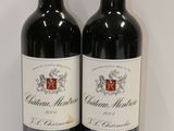 two bottles of red wine sitting on top of a white table
